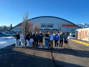 A group of student athletes stands outside a covered indoor track