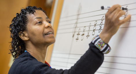 High school music teacher writing on board A music teacher provides a theory lesson on major triads.