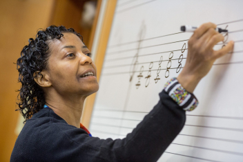 High school music teacher writing on board A music teacher provides a theory lesson on major triads.