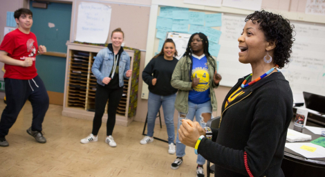 A music teacher leads choir students in a warm-up exercise.