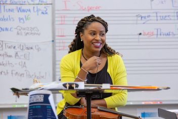 Female orchestra teacher A middle school orchestra teacher listens as her students rehearse.