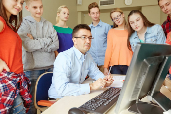 education, school, learning, technology and people concept - group of students and teacher with computer in classroom